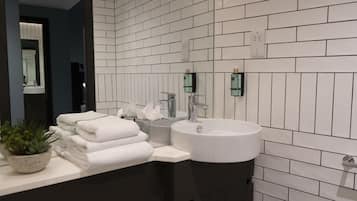 Une salle de bain moderne avec des carreaux de métro blancs, un lavabo blanc et un meuble-lavabo foncé.