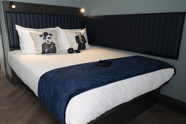 A neatly made bed with a blue and white duvet, two pillows with a panda design, and a remote control on the bed.
