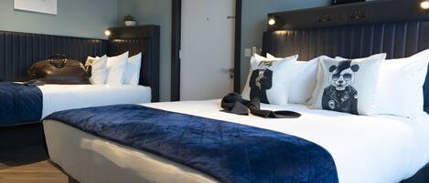 Une chambre d’hôtel avec deux lits, une tête de lit sombre, une horloge et un tableau encadré au mur.