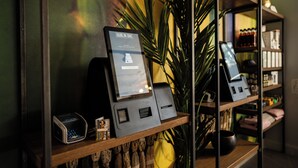A self-service kiosk with a sign reading "Dublin One" in a modern interior with wooden shelves and a potted plant. - Dublin One Hotel (Dublin)