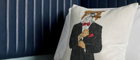 Un cuscino con una grafica decorativa su un letto con testiera imbottita blu.