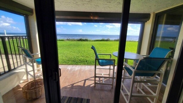 A balcony with a view of the ocean, a table, and two chairs. - Sand Dollar 101 (St. Augustine)