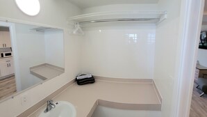 Un baño con lavamanos blanco, espejo y perchero.