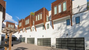 Un immeuble résidentiel moderne doté de plusieurs portes de garage, d’étages supérieurs en bois et surplombant un ciel dégagé.