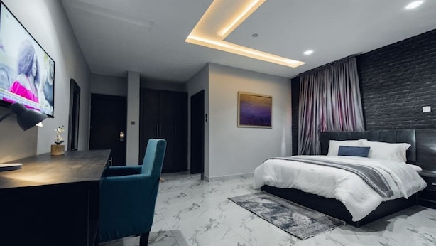 Un dormitorio moderno con una cama, un escritorio y un televisor.
