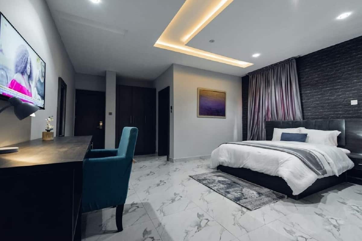 A modern bedroom with a bed, a desk, and a TV.
