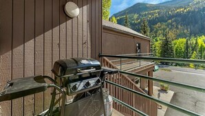 A balcony with a grill, overlooking a forested mountain area. - Convenient 1 Bedroom East Vail Condo by Gorecreek Rentals (Vail)
