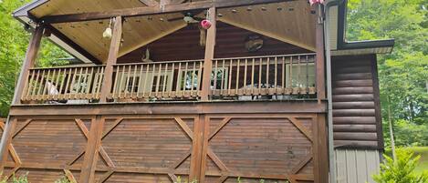 Een houten chalet met balkon, vlag en een rustieke uitstraling.