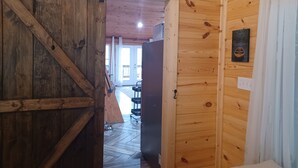 Un interior de madera con una puerta corrediza de estilo rústico, una mesita y una silla al fondo.