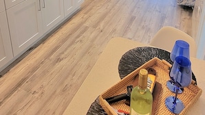 A modern kitchen with white cabinets, a microwave, and a dining area with a table and chairs. - Satellite Motel - License to Chill 115 (Treasure Island)