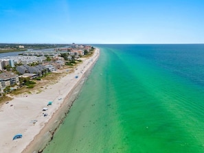 An aerial view of a coastal area with a beach, buildings, and a clear blue sea. - NEWLY RENOVATED EXTERIOR Beachfront Condo, Pool, Gulf Coast Sunsets! (Indian Shores)