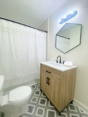 Een bad/douchecombinatie, handdoeken, zeep, toiletpapier