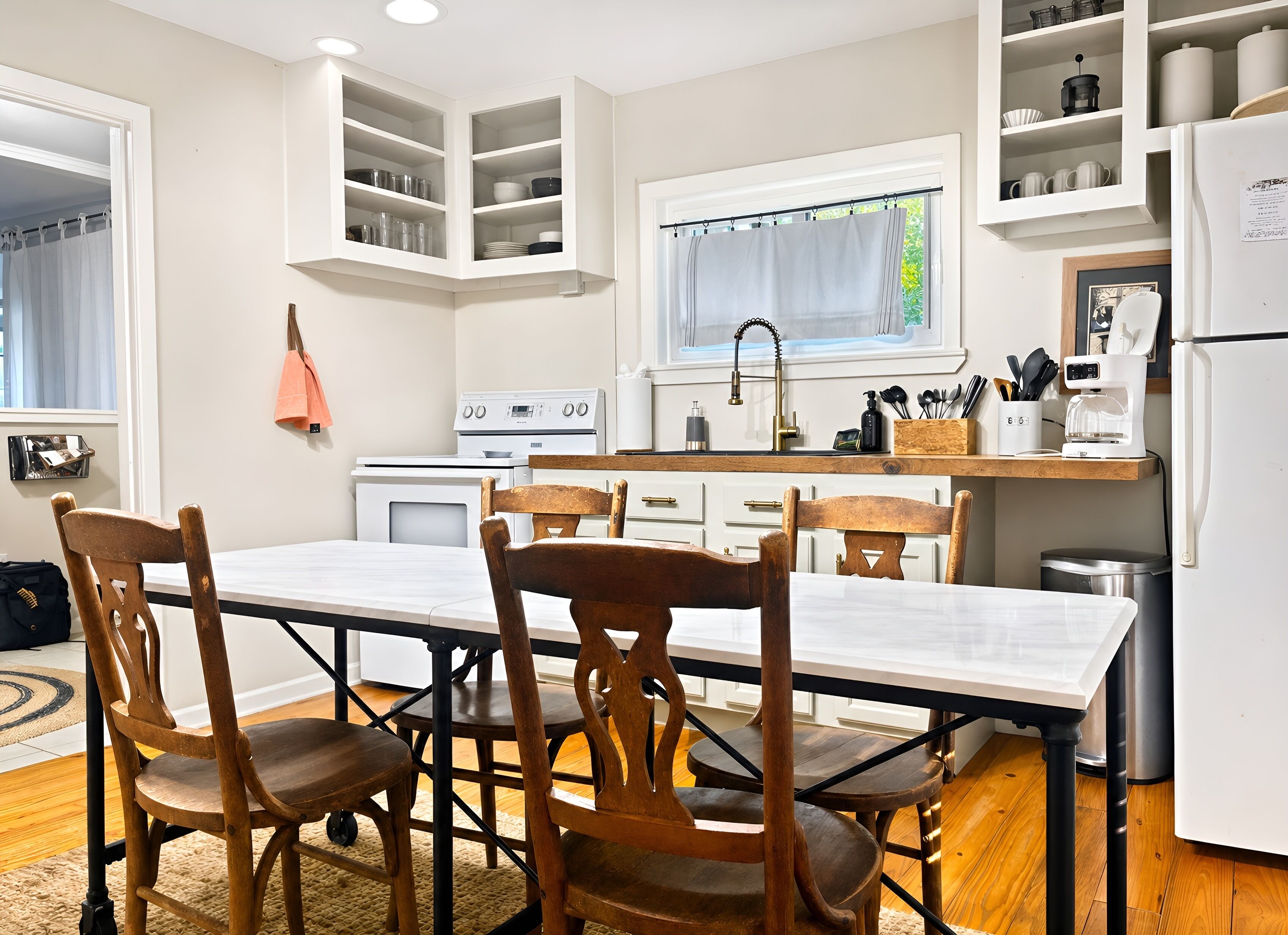 A kitchen with white cabinetry, a dining table with chairs, a stove, and a refrigerator.