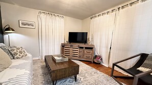 A living room with a sofa, a coffee table, a TV on a wooden cabinet, and a chair. - PRIVATE Cleveland St. Cottage~Walk Folsom Village (Folsom)