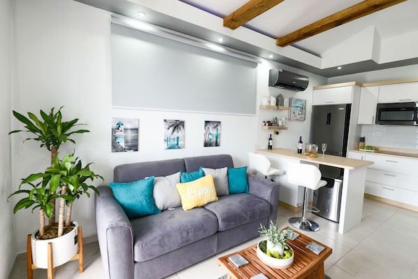 A modern living room with a grey sofa, a coffee table, and a potted plant. - VILLA WITH POOL STEPS FROM THE BUYÉ BEACH (Cabo Rojo)