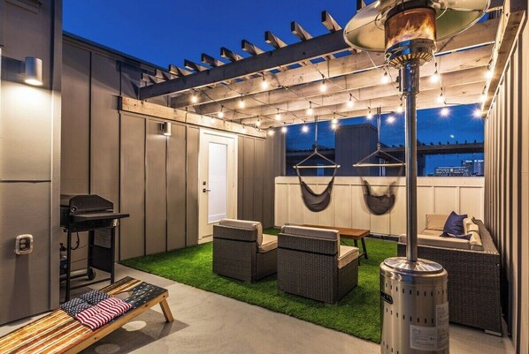 Relax in a shaded patio area with a grill and comfortable seating for two.