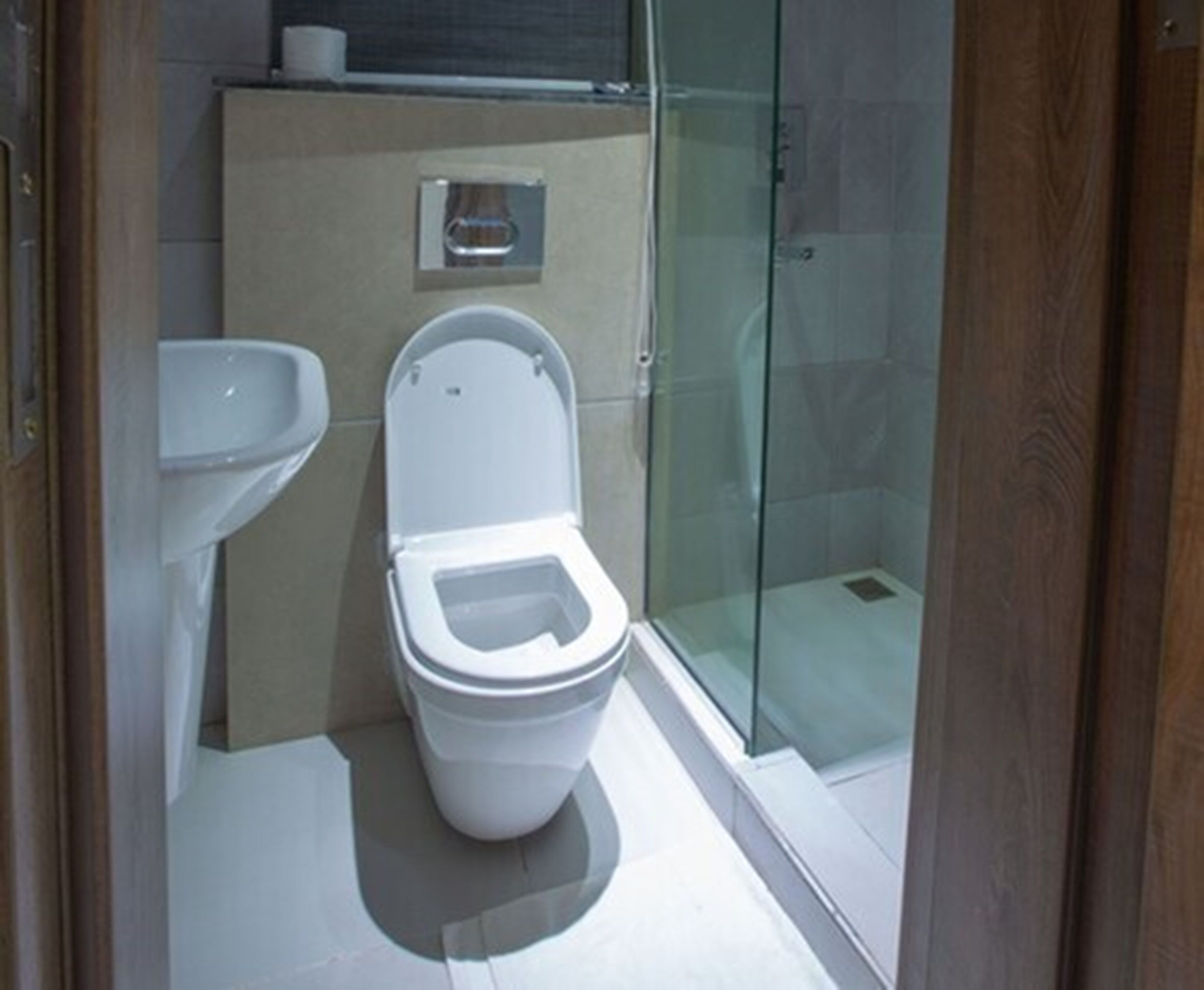 A modern bathroom with a toilet, sink, and glass shower enclosure.