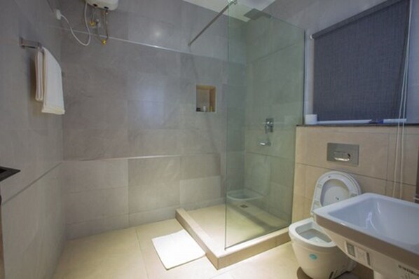 A modern bathroom with a glass-enclosed shower, a toilet, and a sink.