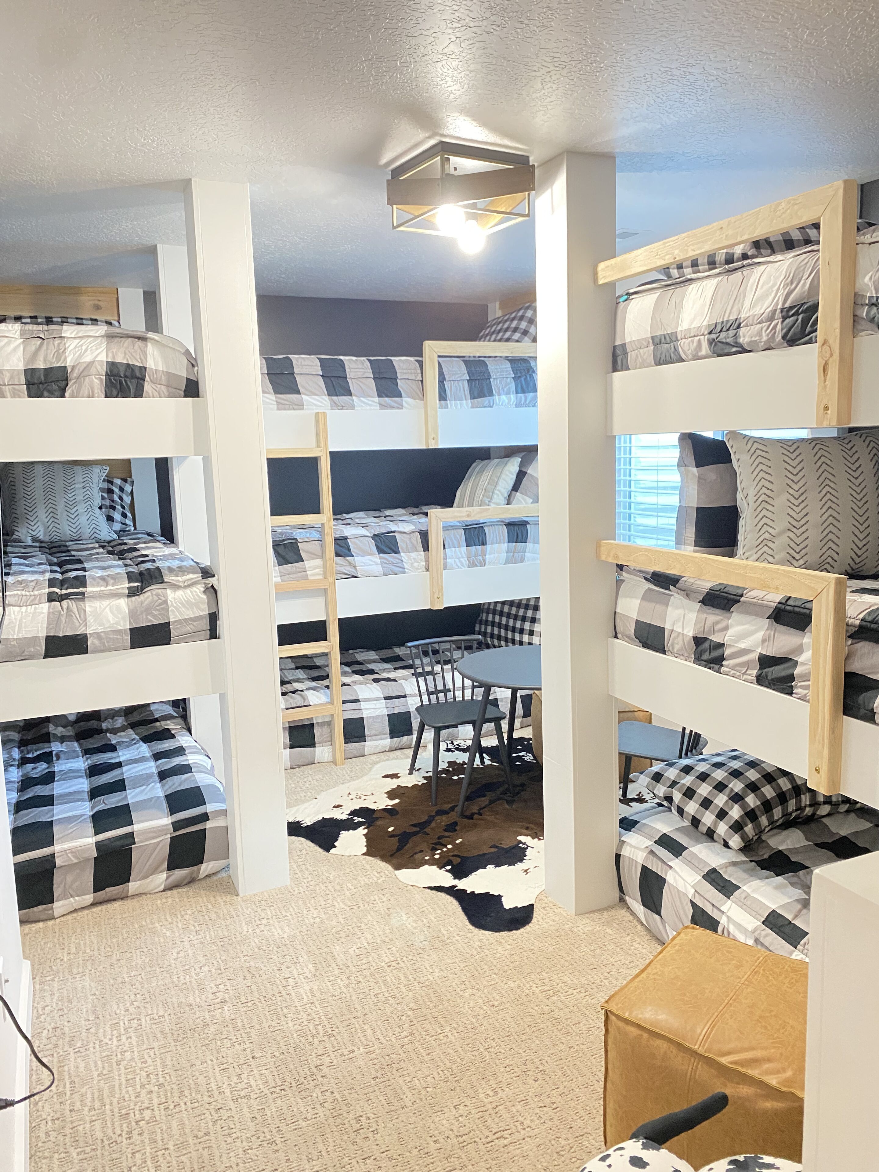 A bunk bed room with a cowhide rug, a wooden table, and a chair.