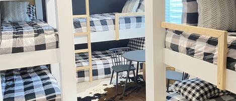 A bunk bed room with a cowhide rug, a wooden table, and a chair.