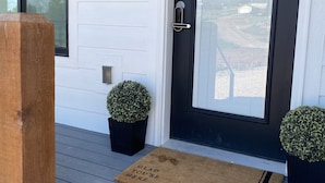 Une porte d’entrée sur laquelle on peut lire le numéro « 2690 », une enseigne indiquant « Sweetwater and Wine », et deux plantes en pot de chaque côté.