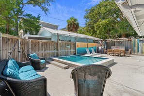 A backyard with a swimming pool, wicker furniture, and a wooden fence. - One Lot off the Beach, a Sophisticated Chic East Beach Retreat w Heated Pool (Saint Simons Island)