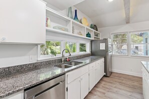 A kitchen with granite countertops, stainless steel appliances, and white cabinetry.