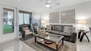 A modern living room with a glass coffee table, leather sofa, and wicker chairs.