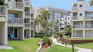 A multi-story hotel with balconies, a well-maintained lawn, and a clear sky.