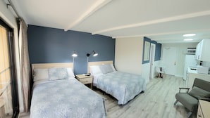 A hotel room with two beds, a desk, and a chair.