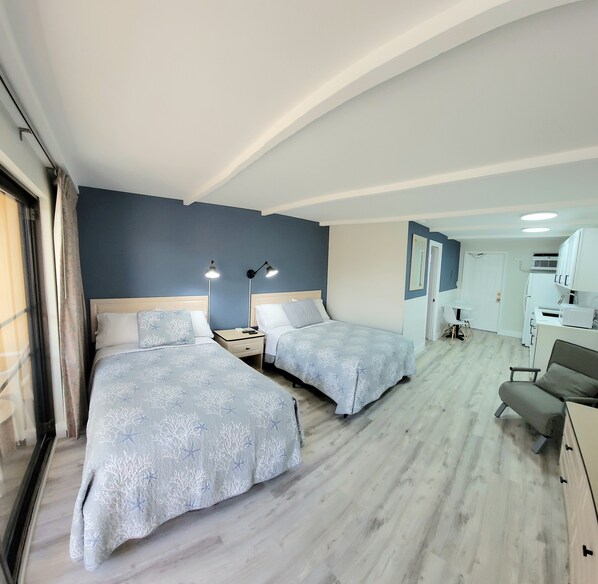 Une chambre d’hôtel avec deux lits, un bureau et une chaise.