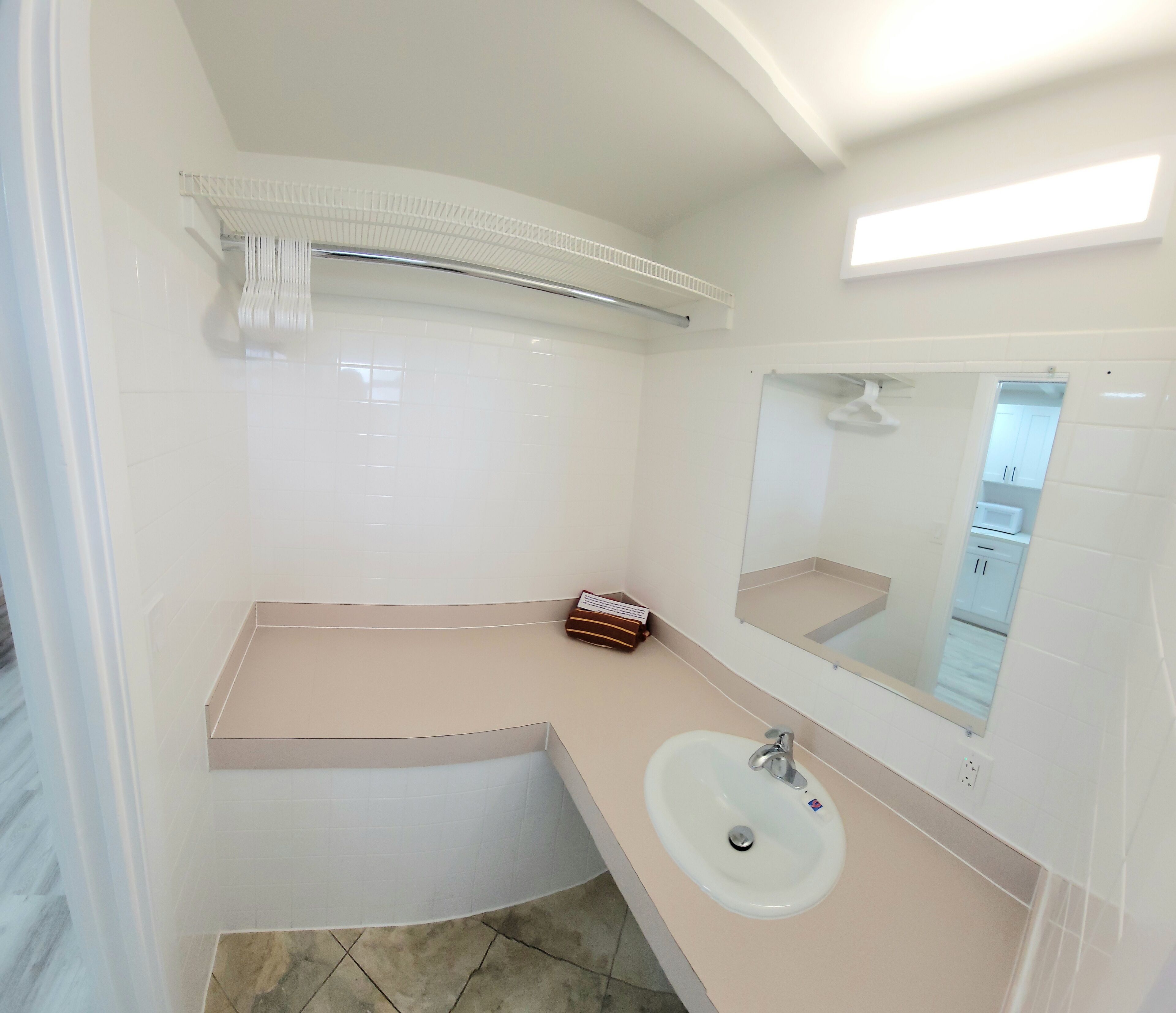 Une salle de bain moderne avec un lavabo blanc, un miroir et un porte-serviettes.