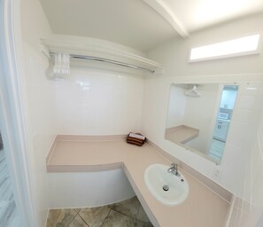 Une salle de bain moderne avec un lavabo blanc, un miroir et un porte-serviettes.