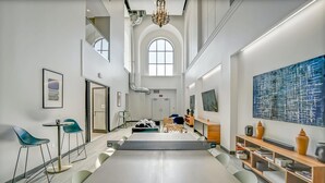 Ein geräumiges, modernes Interieur mit einem großen zentralen Tisch, einer Sitzecke und Kunstwerken an den Wänden.