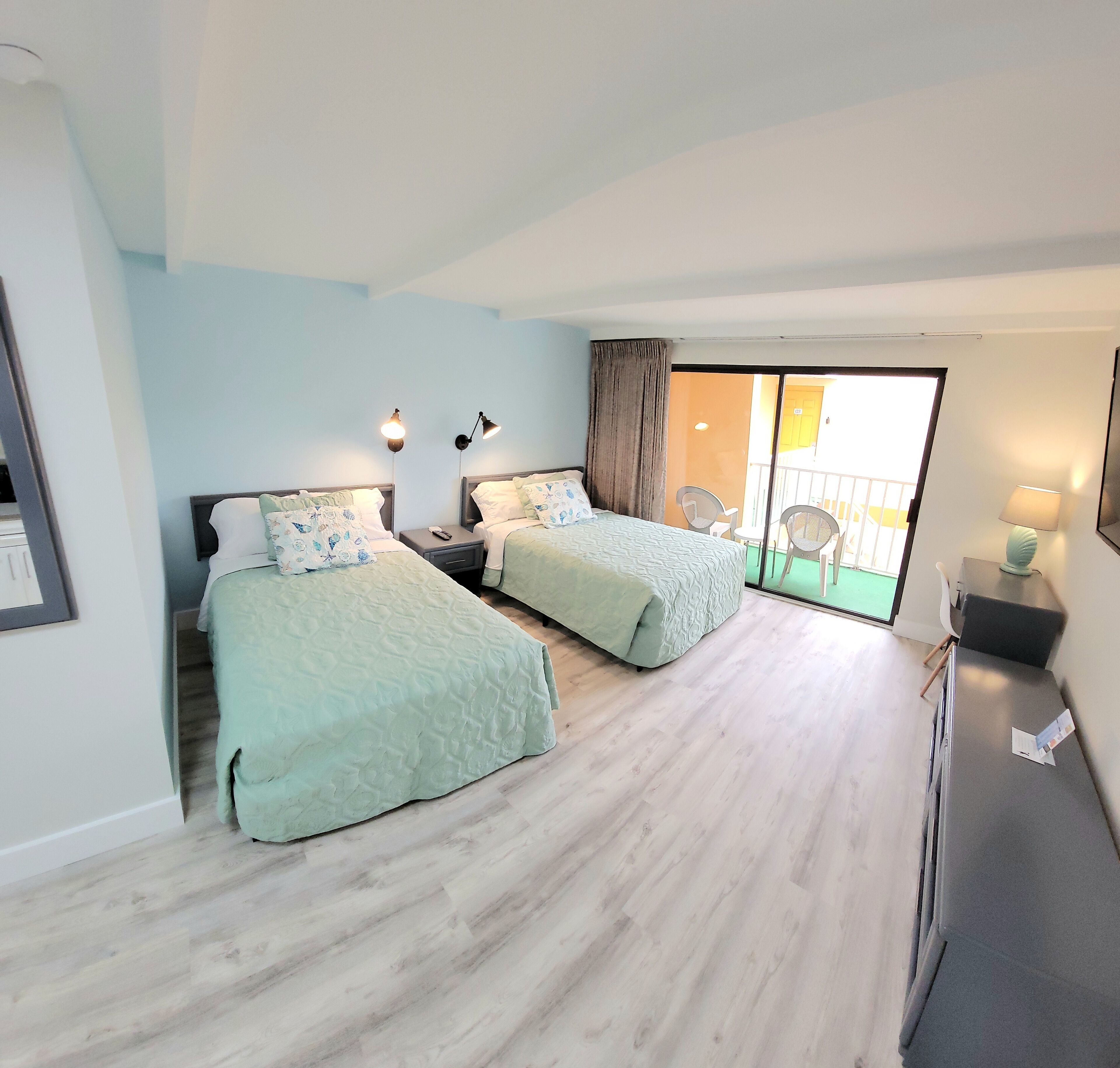 Une chambre d’hôtel avec deux lits, un balcon et un bureau.