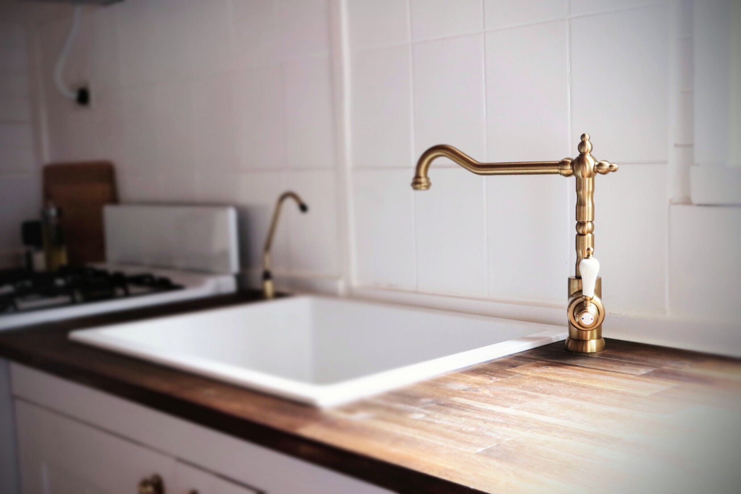 Eine Küche mit einem weißen Spülbecken, einem goldenen Wasserhahn und einer Holz Arbeitsplatte.