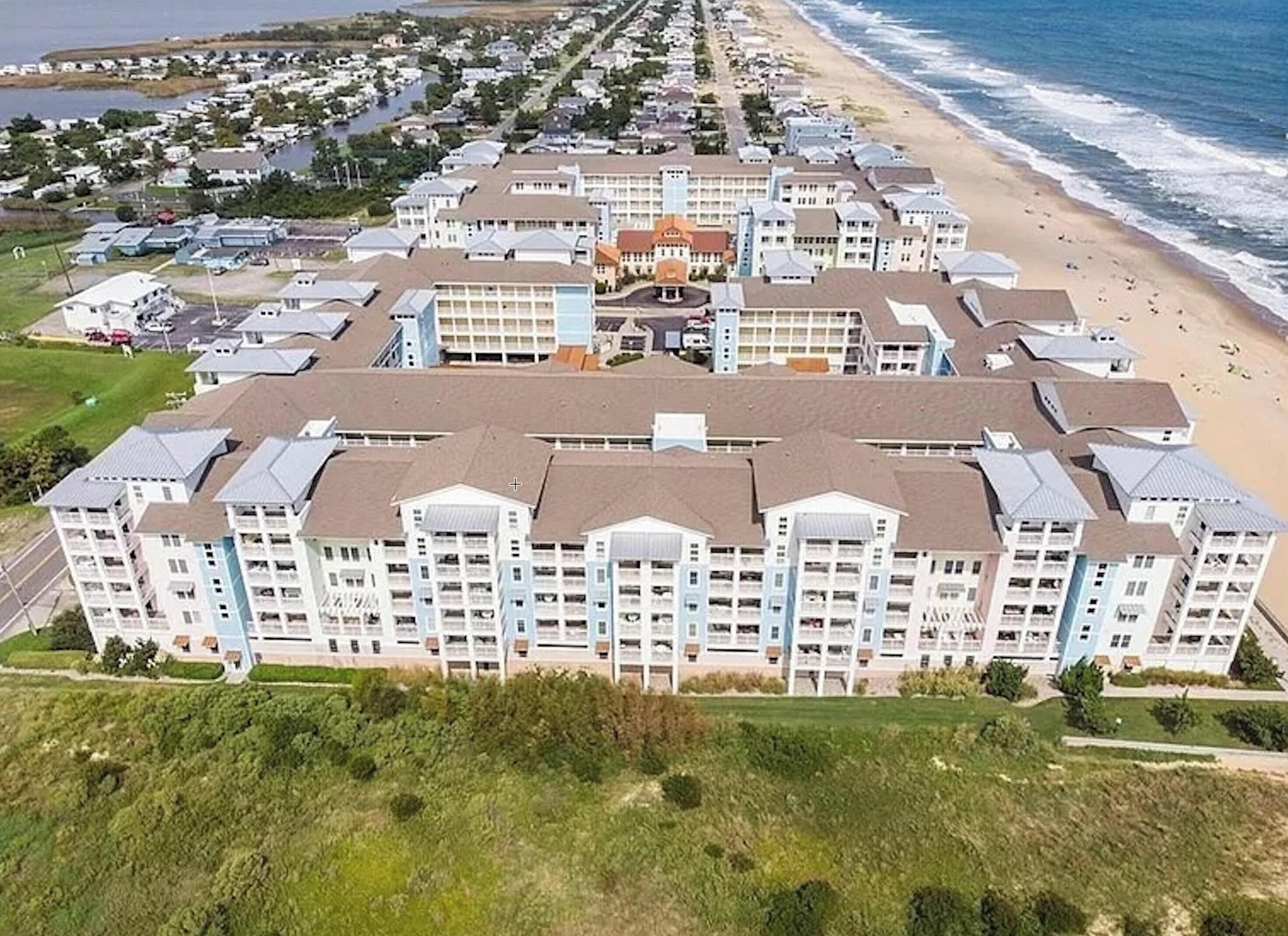 A beachfront hotel with multiple buildings, a central courtyard, and a beach view.