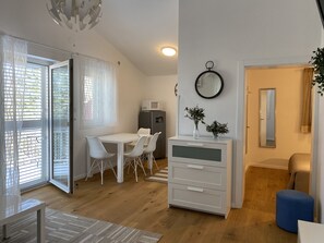 Un salon moderne avec un coin repas, une commode blanche et un pouf bleu.