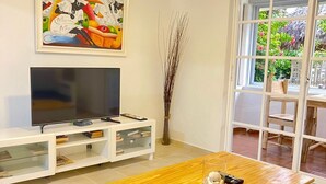 Un salon avec un téléviseur, un meuble de rangement blanc et une table basse en bois.