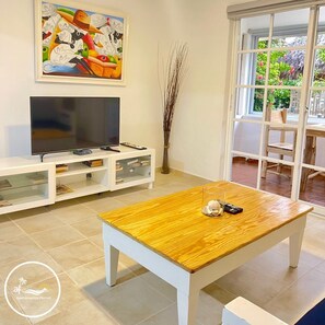 Un salon avec un téléviseur, un meuble de rangement blanc et une table basse en bois.