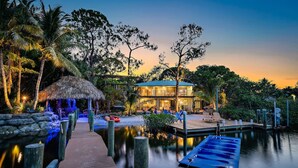 A resort with a wooden dock leading to a glass building, surrounded by tropical vegetation and a calm water body. - THE RIVER HOUSE, 21 Foot Boston Whaler Included (Jupiter)