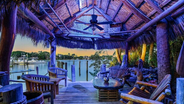 A wooden deck with thatched roof seating and a view of the water. - THE RIVER HOUSE, 21 Foot Boston Whaler Included (Jupiter)