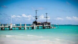 Un muelle se adentra en aguas turquesas, con un barco amarrado al final.