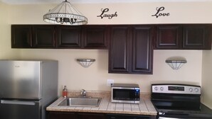 A kitchen with dark cabinets, a stainless steel refrigerator, a microwave, and a stove.