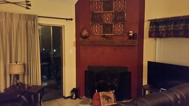 A living room with a fireplace, a sofa, a lamp, and a view of the outdoors.