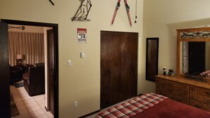 A bedroom with a bed, a ceiling fan, a wardrobe, a mirror, and a poster on the wall.
