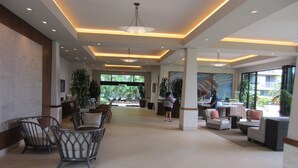 A spacious lobby with modern furniture, large windows, and indoor plants. - Whaler Tower II - 1 Bedroom Condo with Beautiful Ocean View (Lahaina)