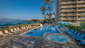 A pool area with lounge chairs, a hot tub, and palm trees. - Whaler Tower II - 1 Bedroom Condo with Beautiful Ocean View (Lahaina)
