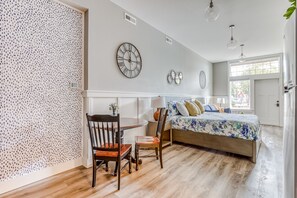 Cozy retreat with a large bed, round table, and wall clock.