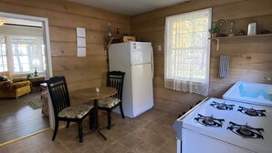 Una cocina compacta con un refrigerador blanco, una estufa a gas y una mesa de comedor con sillas.